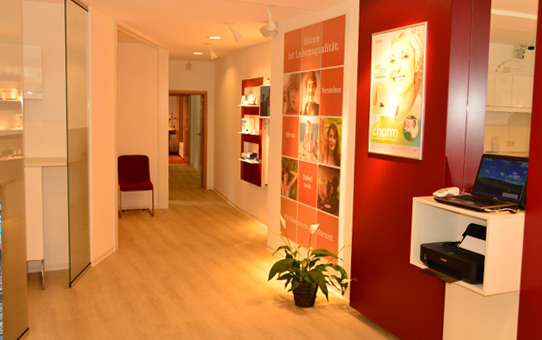 Moderner und heller Flur einer Hörakustik-Filiale mit Infowand und Empfangsbereich.